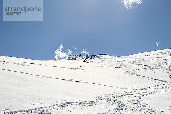 Älterer Mann fährt mit Skiern den schneebedeckten Berg hinunter  Fernsicht aus niedrigem Winkel  Steiermark  Tirol  Österreich