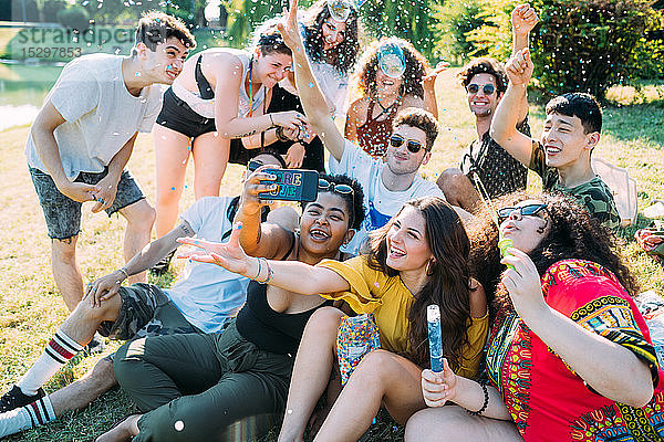 Eine Gruppe von Freunden nimmt Selfie  spielt mit Konfetti im Park