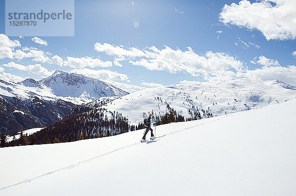 Reife Frau beim Schneeschuhwandern auf schneebedecktem Berghang  Fernsicht  Steiermark  Tirol  Österreich