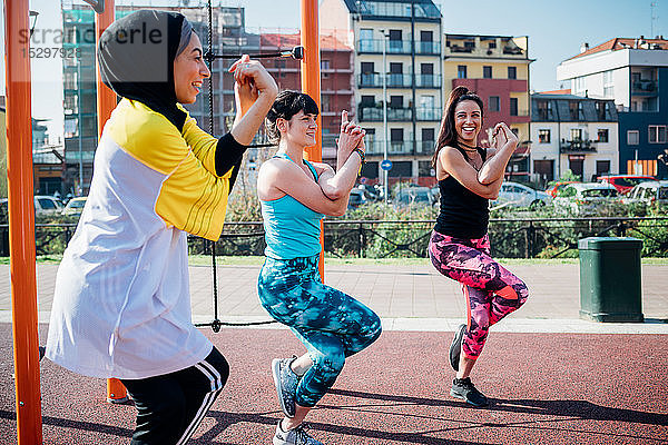 Calisthenics-Kurs im Fitnessstudio im Freien  junge Frauen balancieren auf einem Bein  Seitenansicht