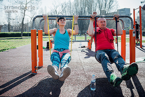 Gymnastikkurs im Freien  reifer Mann und junge Frau üben am Barren