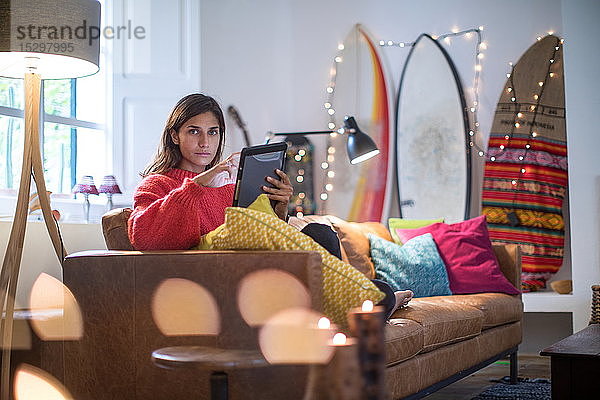 Junge Frau auf Wohnzimmer-Sofa mit digitalem Tablet  Portrait