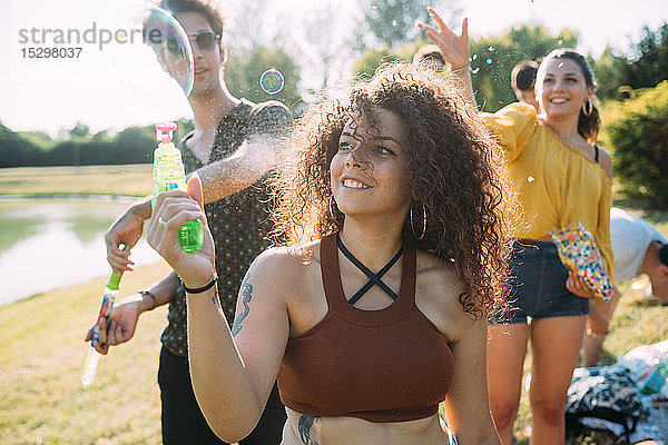 Gruppe von Freunden spielt mit Blasenpistole im Park