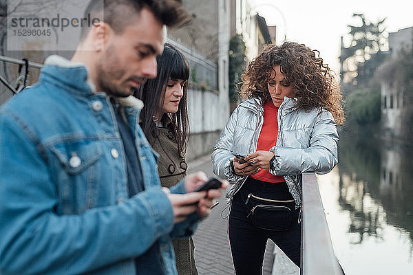 Freunde mit Smartphone am Fluss  Mailand  Lombardei  Italien