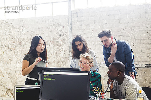 Zuversichtliche junge Berufstätige planen bei der Programmierung am Computer am Arbeitsplatz