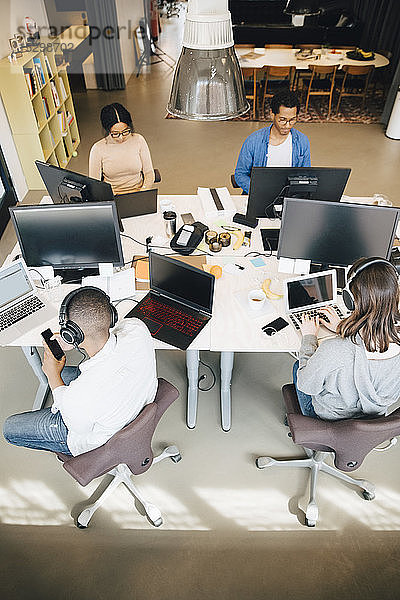 Hochwinkelansicht von männlichen und weiblichen Programmierern  die im Büro am Schreibtisch sitzen