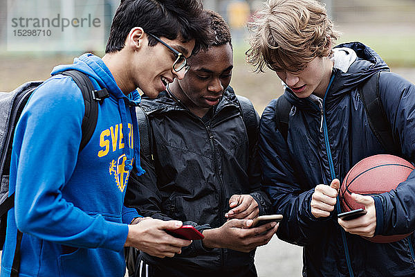 Freunde unterhalten sich beim Blick auf das Smartphone auf dem Spielfeld