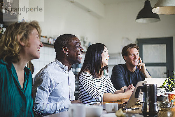 Lächelnde Unternehmer sitzen  während sie im Büro auf den Schreibtisch schauen