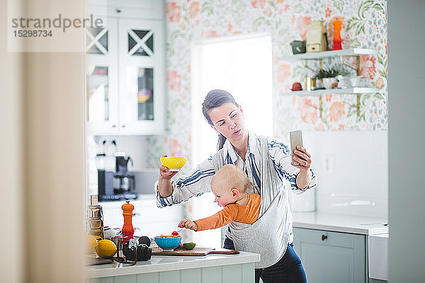 Multi-Tasking-Blogging über Mutter-Essen  während die Tochter in der Küche zu Hause ist
