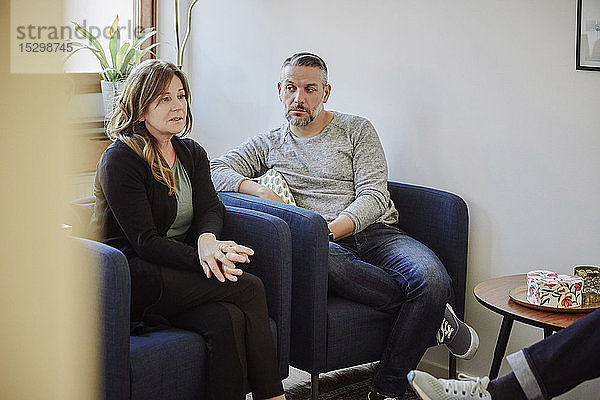 Unzufriedenes Paar teilt Probleme mit dem Therapeuten  während es im Gemeindezentrum sitzt