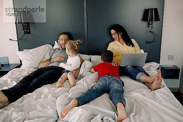 Glückliche Familie im Hotelzimmer im Bett während der Ferien