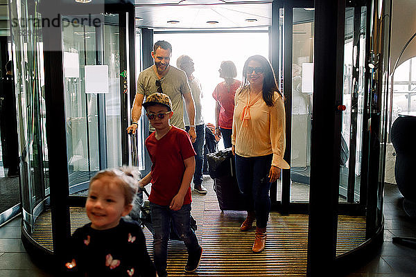 Lächelnde Familie betritt Hotel während des Urlaubs