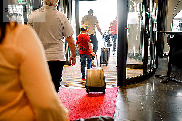 Rückansicht der Familie zu Fuß am Hotelausgang