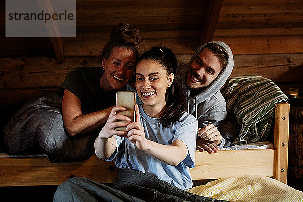 Lächelnde junge Frau beim Selbermachen mit Freunden im Ferienhaus