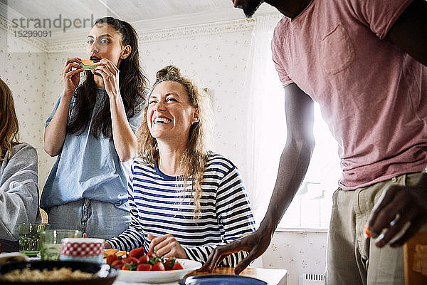 Niedriger Blickwinkel auf glückliche Freunde  die das Essen in geselliger Runde zu Hause genießen