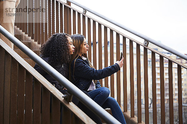 Teenager-Mädchen  das mit einer Freundin auf der Treppe sitzend Selbstgespräche führt