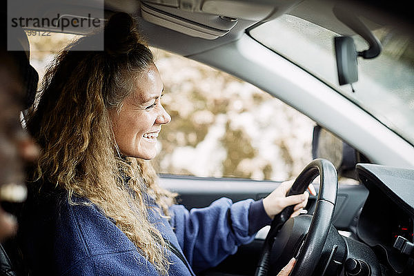 Seitenansicht einer glücklichen jungen Frau beim Autofahren