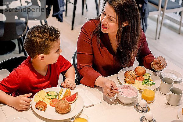 Schrägaufnahme einer Mutter  die mit ihrem Sohn spricht  während sie während des Frühstücks im Restaurant am Tisch sitzt