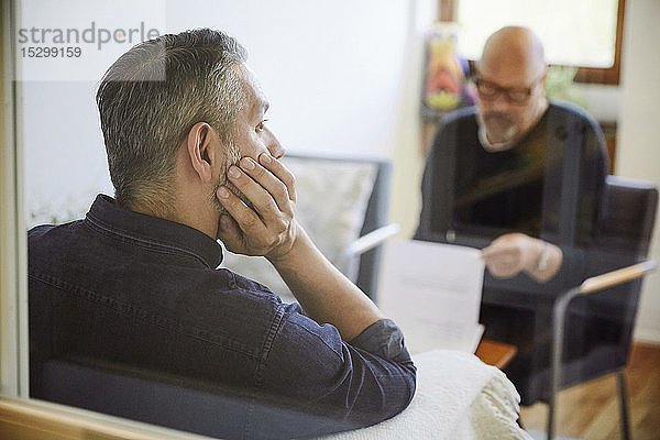 Nachdenklicher männlicher Patient sitzt bei Therapie-Workshop