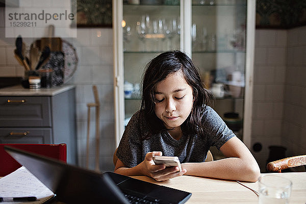 Junge E-Learning während der Nutzung eines Smartphones für Hausaufgaben zu Hause