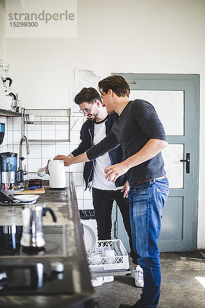 Junge Geschäftsleute kochen Kaffee in der Küche an einem kreativen Arbeitsplatz