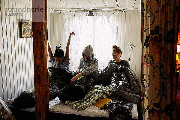 Männliche und weibliche Freunde wachen im Bett gegen das Fenster in einer Hütte auf
