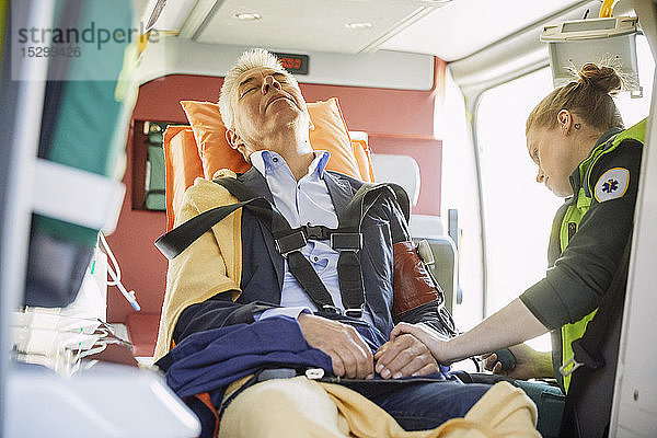 Sanitäterin kontrolliert den Blutdruck des Mannes im Krankenwagen