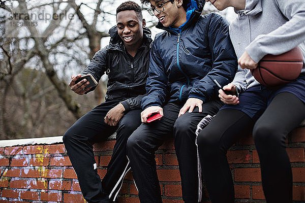 Lächelnder Teenager  der nach dem Basketballtraining im Winter mit Freunden ein Selfie mitnimmt