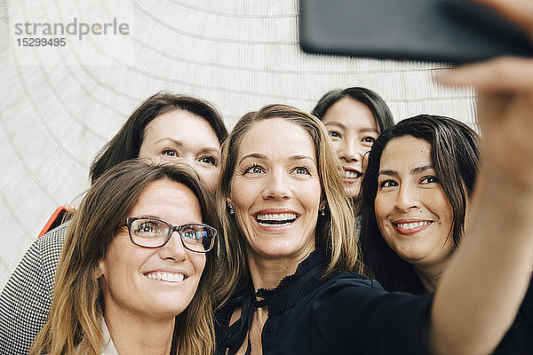 Lächelnde Geschäftsfrau nimmt sich während der Konferenzveranstaltung mit weiblichen Fachleuten im Büro ein