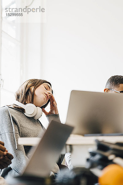 Erschöpfte Computerhackerin sitzt am Schreibtisch im Büro