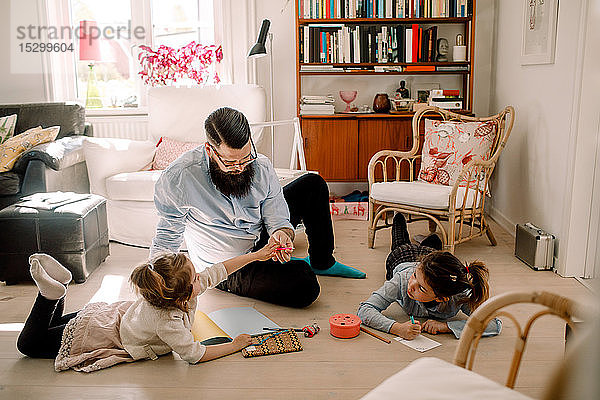 Vater spielt mit Töchtern zu Hause im Wohnzimmer