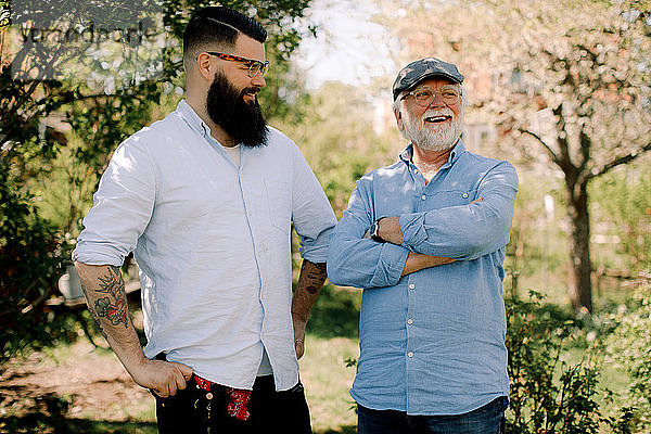 Lächelnder älterer Vater und Sohn stehen im Hof