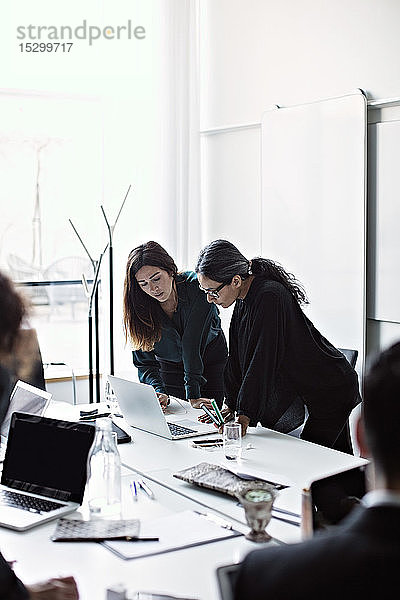 Geschäftsfrauen arbeiten über Laptop am Konferenztisch im Sitzungssaal