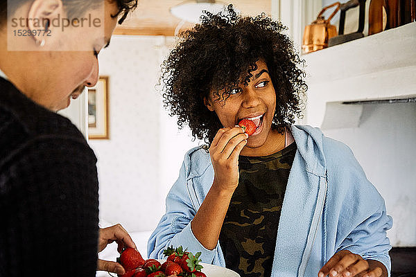 Freunde essen Erdbeeren im Stehen zu Hause