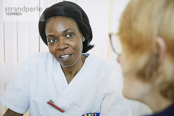 Zuversichtlicher weiblicher Arzt im Gespräch mit Frau in der Klinik