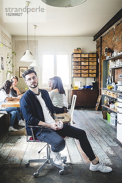 Porträt eines selbstbewussten jungen männlichen IT-Experten  der in einem kreativen Büro auf einem Stuhl sitzt