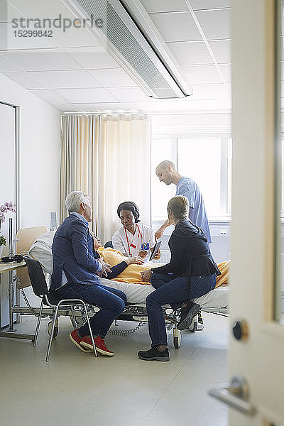 Mitarbeiter des Gesundheitswesens diskutieren mit der Patientin und ihren Freunden auf der Krankenhausstation
