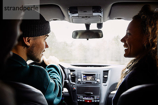 Männliche und weibliche Freunde unterhalten sich während einer Autofahrt