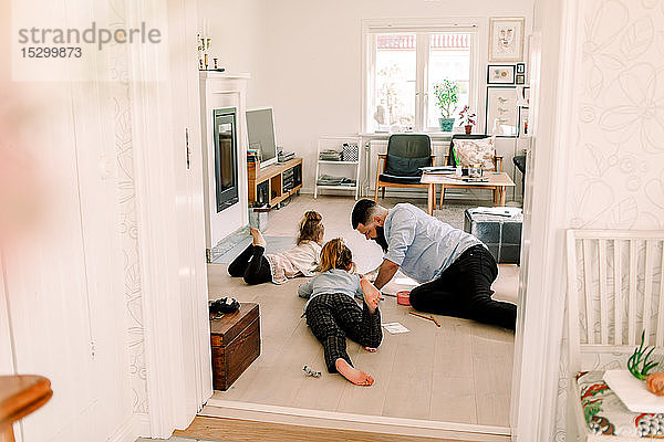 Mittelgroßer erwachsener Mann  der mit Töchtern zeichnet  während er sich zu Hause im Wohnzimmer ausruht