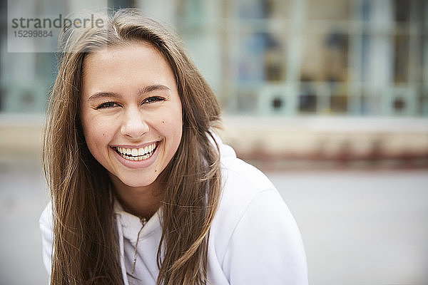 Porträt eines lächelnden Teenagers  der auf dem Schulhof sitzt