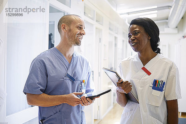 Glückliche Mediziner in Uniform diskutieren auf dem Krankenhauskorridor