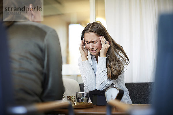 Stressgeplagter  weinender Teenager mit dem Kopf in der Hand  der Probleme mit dem Therapeuten des Wellness-Zentrums teilt