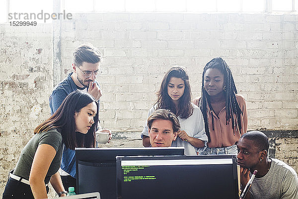 Seriöse Computerprogrammierer schauen beim Brainstorming am Arbeitsplatz auf den Computerbildschirm