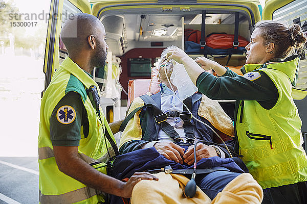 Männliche und weibliche Rettungssanitäter behandeln Geschäftsmann mit HLW außerhalb des Krankenwagens