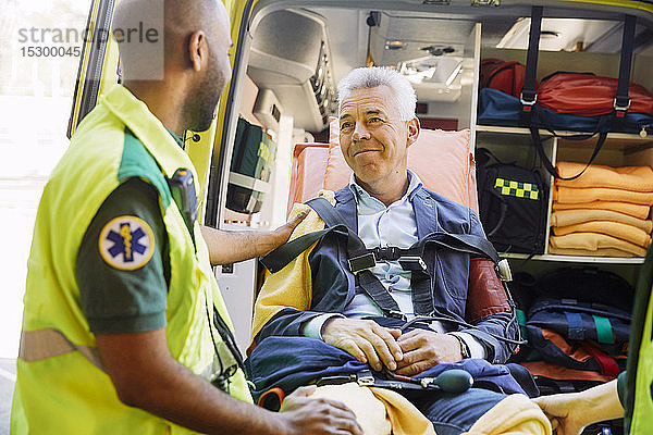 Männlicher Rettungssanitäter tröstet reifen Patienten im Krankenwagen