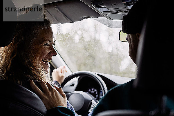 Fröhliche Frau unterhält sich mit einem Freund  während sie im Auto unterwegs ist