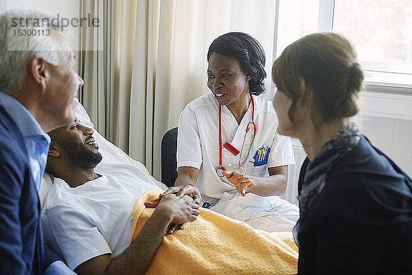 Mitarbeiter des Gesundheitswesens ermutigen Patient und seine Familie auf der Krankenhausstation