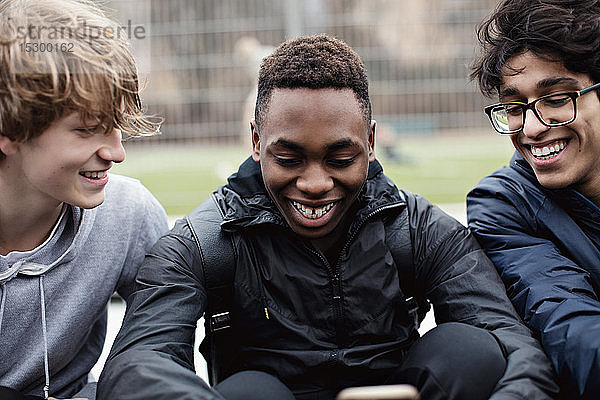 Fröhliche männliche Freunde nutzen soziale Medien nach dem Sporttraining im Winter