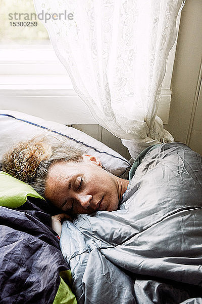 Hochwinkelansicht einer mittelgroßen erwachsenen Frau  die auf einem Bett in einer Hütte schläft