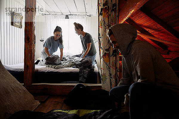 Männliche und weibliche Freunde falten Decken in einer Hütte